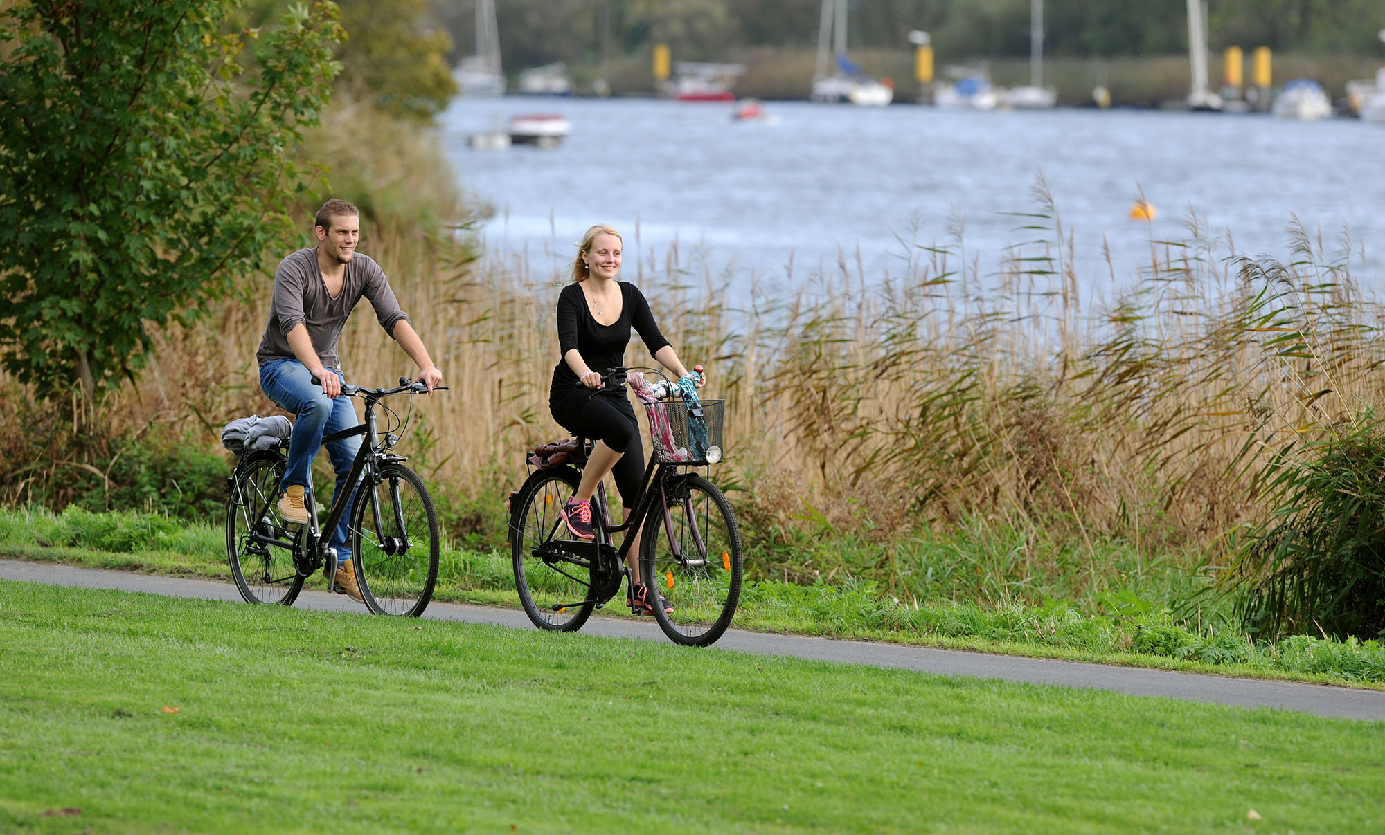 Ein Radfahrer und eine Radfahrerin radeln entlang des Weser-Ufers