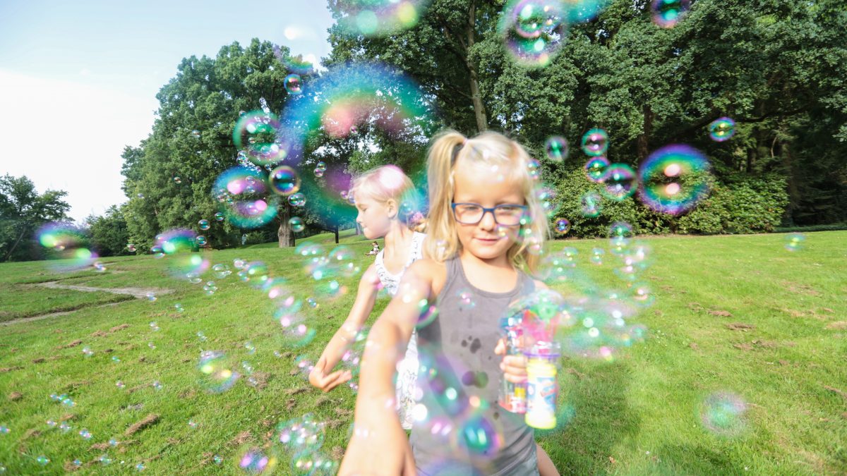 Zwei Mädchen spielen mit Seifenblasen im Park