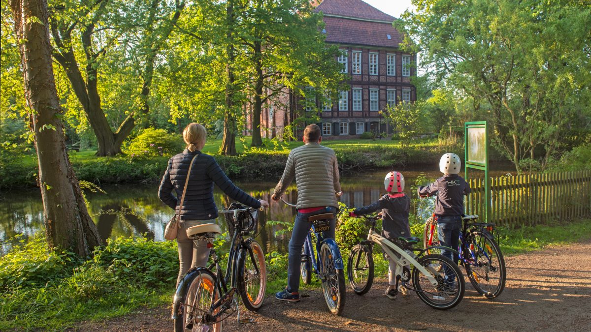Familie mit Fahrrädern guckt auf das Schloss Schönebeck