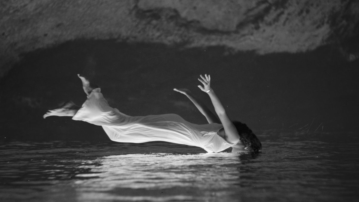 Schwarzweiß Fotografie von einer Frau, die im Wasser zu schweben scheint