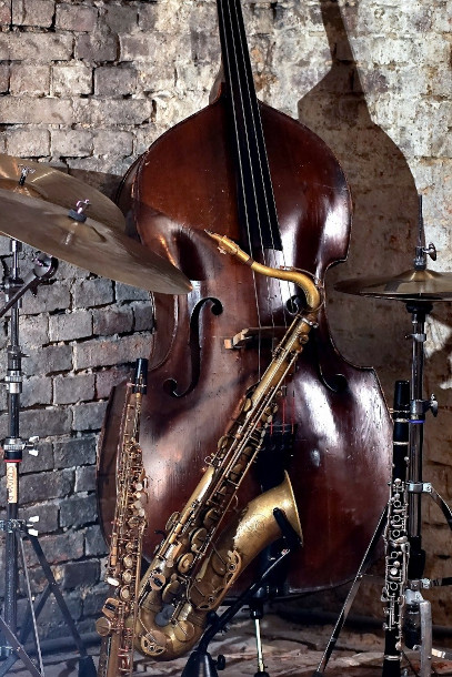 Ein Cello und ein Saxophone stehen vor einer grauen Steinwand