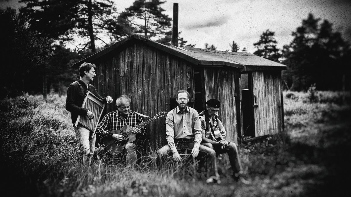 Schwarzweiß Bild von ein paar Männern, die draußen vor einer kleinen Hütte sitzen
