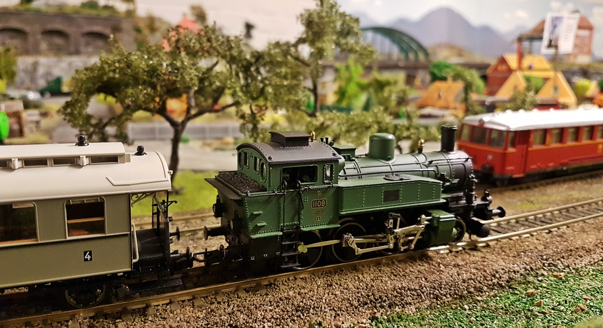 Grüne Lok einer Modeleisenbahn fährt auf den Schienen.