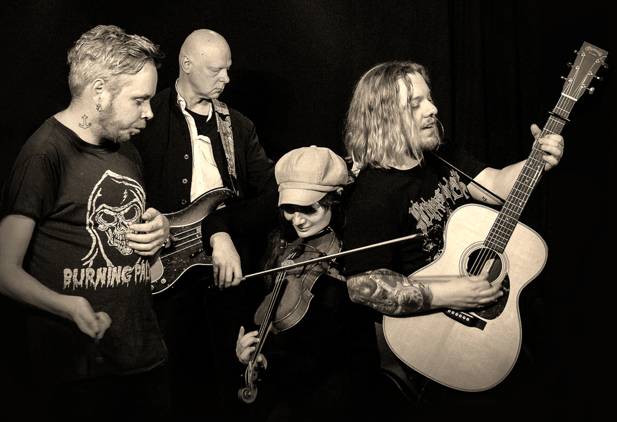 Schwarzweiß Bild von 4 Männern, die verschiedene Musikinstrumente in der Hand halten