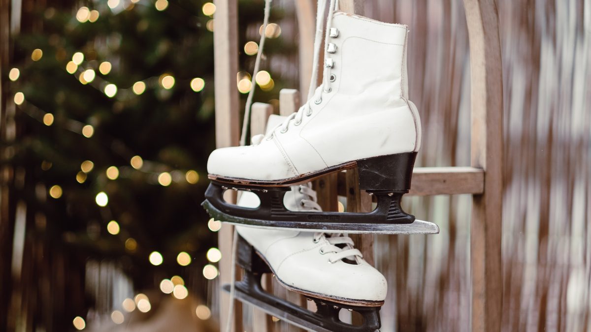 Ein Paar Schlitzschuhe hängen an einer Wand. Im Hintergrund steht ein geschmückter Tannenbaum